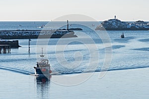 Small fishing boat in the port of Svolvaer on the Lofoten islands in Norway with snow on clear day with blue sky