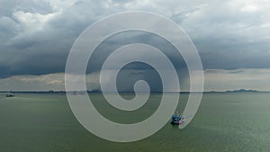 Small fishing boat sailing in sea storm background