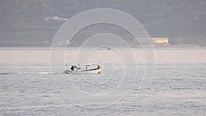 Small fishing boat slowly motoring along coast at golden hour