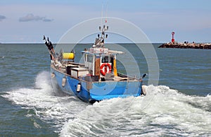 fishing boat swiftly cutting through the waves of the Mediterranean Sea just after leaving a port photo