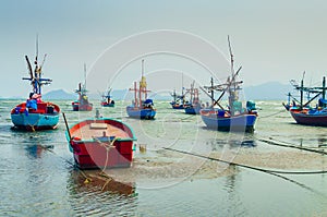 Small fishing boats anchor at beach in cloudy sunset sky