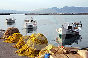 Small fishing boats floating in the pretty harbor in Nafplio in Greece with nets