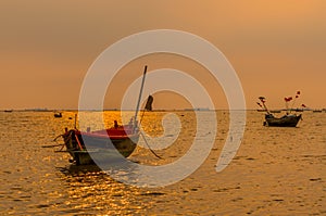 Small fishing boats on the sea during sunset and clouds.