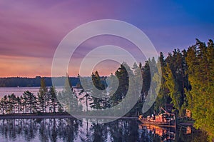 Small fishing or pleasure boat boat moored on Paijanne lake. Beautiful sunrise scape with stone beach, pine forest and water. Lake