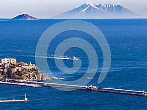 Small fishing ship coming to a port, big island mountain in the background