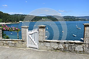 Small fishing village with boats and beach. View with white wooden door and flowers. Redes, Galicia, Spain. photo