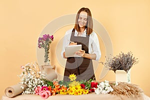 Small floral business owner. Professional florist workshop. Saleswoman at the floral shop holding clipboard writing and making