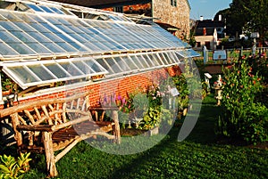 A small flower and herb garden grows outside of a green house