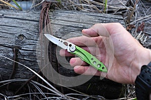 Small folding knife in the hand of a man.