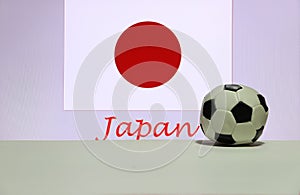 Small football on the white floor and Japanese nation flag with the text of Japan background.