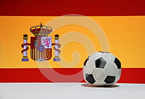 Small football on the white floor and Spanish nation flag background.