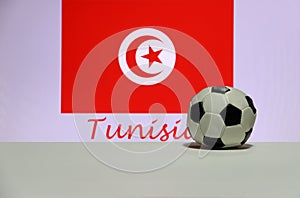 Small football on the white floor and Tunisian nation flag with the text of Tunisia background.