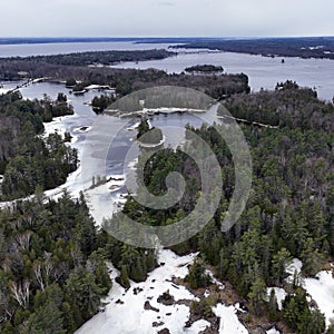 Small forested islands in the Ottawa River in late winter surrounded by ice and open water