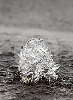 Small fountain of water gushing from a hole in the road