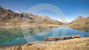Small freight train on rails near a high mountain lake photo