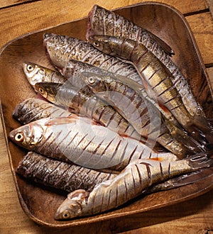 Small fresh fish chub on a wooden plate on the wooden box. Top view