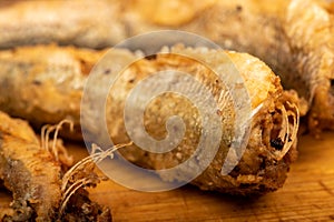 Small fried fish on a wooden board, close-up, selective focus