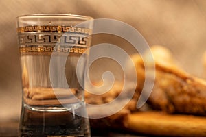 A small fried fish on a wooden board, pieces of bread and a glass of vodka, close-up, selective focus