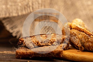 A small fried fish on a wooden board, pieces of bread and a glass of vodka, close-up, selective focus