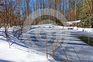 Small frozen pond is surrounded by very deep snow in Pisgah Forest