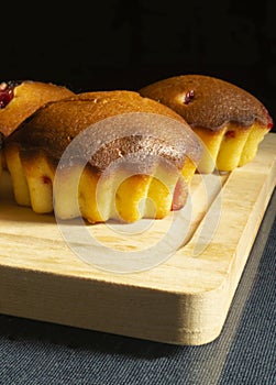 Small fruit cakes with wooden board on glass table