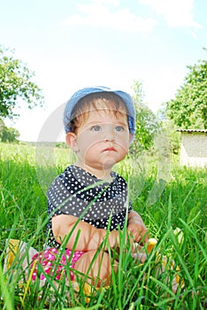 Small, funny girl sitting in the grass