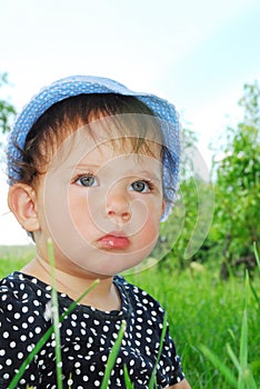 Small, funny girl sitting in the grass