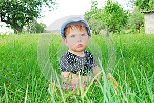 Small, funny girl sitting in the grass