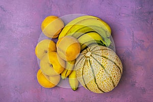 Small Gaul melon with bunch of bananas and yellow peaches photo