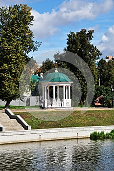 A small gazebo under a green roof in the park.