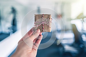 Small gift box with bow in woman hand in the gym opposite the equipment and jogging simulators. Symbol and concept of discount