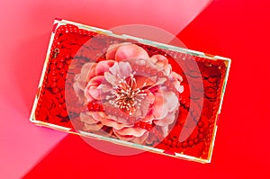 Small gift box with flower, little hearts and beads on duotone pink red background