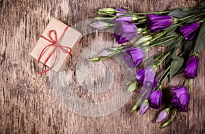 A small gift box and flowers on an old wooden background.