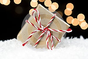 Small gift box wrapped in brown paper and twine wedged in white