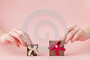 Small gift boxes in women`s hands on a pink background. Festive concept for Valentine`s day, Mother`s day or birthday