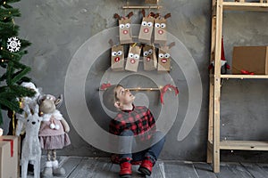 Small gift craft packaging advent calendar hanging on the wall, boy looking at gifts Christmas advent calendar, crafts