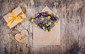 A small gift with a gold ribbon, an envelope with flowers and a heart. Romantic concept.
