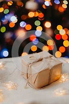 small gift laying on white sweater, decorated Christmas tree on background.