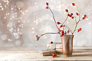 Small gift parcels and rosehip branches on a rustic wooden table