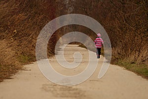 small girl alone on the road with trees