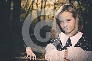 Small girl alone in wild forest in style of halloweeen witch