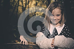 Small girl alone in wild forest in style of halloweeen witch