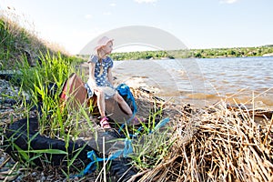 Small girl on the bank of river with rubbish