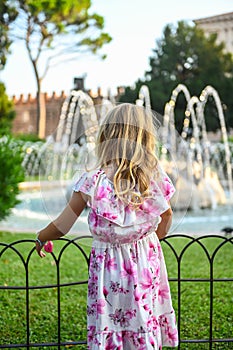 Small girl in beautiful dress admiring fountain in Verona Italy