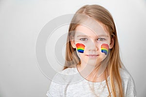 Small girl painted cheeks a rainbow. stay home. photo