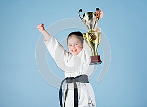 Small girl with champion cup. martial arts. winner little girl in gi sportswear. practicing Kung Fu. childhood. knockout