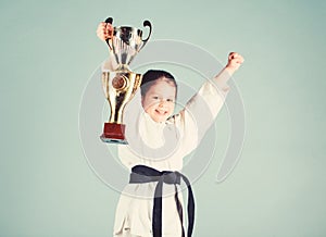 Small girl with champion cup. martial arts. winner little girl in gi sportswear. practicing Kung Fu. childhood. knockout