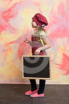 Small girl chef in hat, apron with blackboard