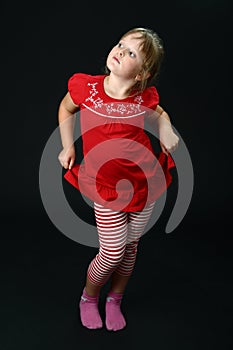 Small girl dancing in red casual clothes on black