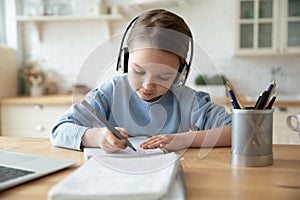 Girl in headphones learning at home doing homework using laptop